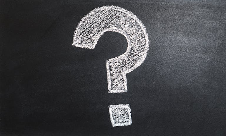 Chalk-drawn question mark on blue background representing the question: When should you insure your nonprofit?