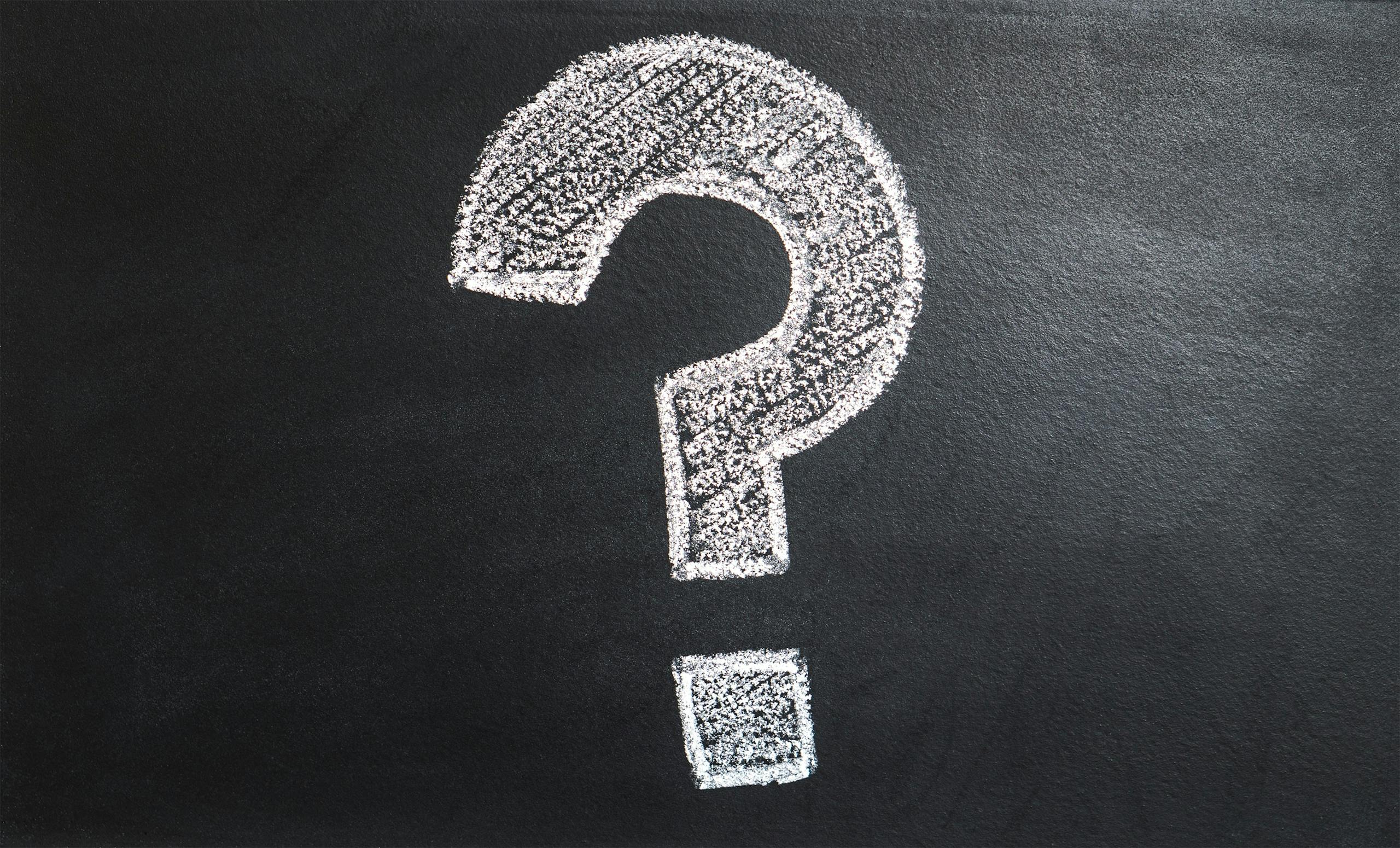 Chalk-drawn question mark on blue background representing the question: When should you insure your nonprofit?