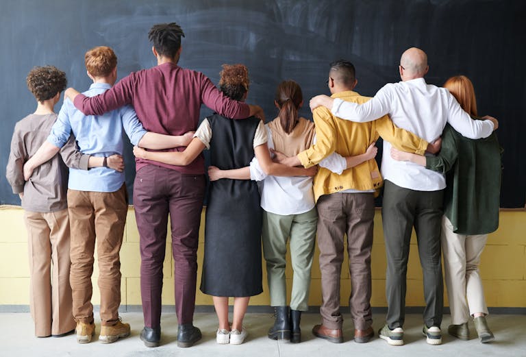 Diverse group of employees standing together with arms linked, symbolizing workplace unity and the importance of Employment Practices Liability Insurance.