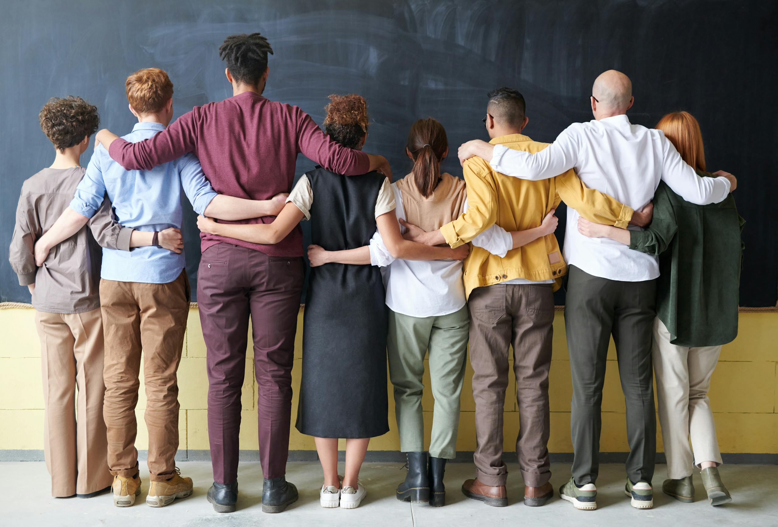 Diverse group of employees standing together with arms linked, symbolizing workplace unity and the importance of Employment Practices Liability Insurance.